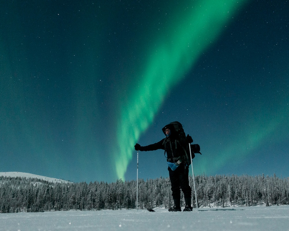 12.2.2022 Man skiing under the northern ligths at Pyhäjärvi, Kittilä Finland.