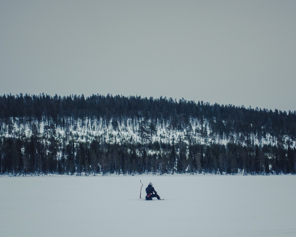 20.3.2020 Man ice fishing in remote lake at Arctic Circle.