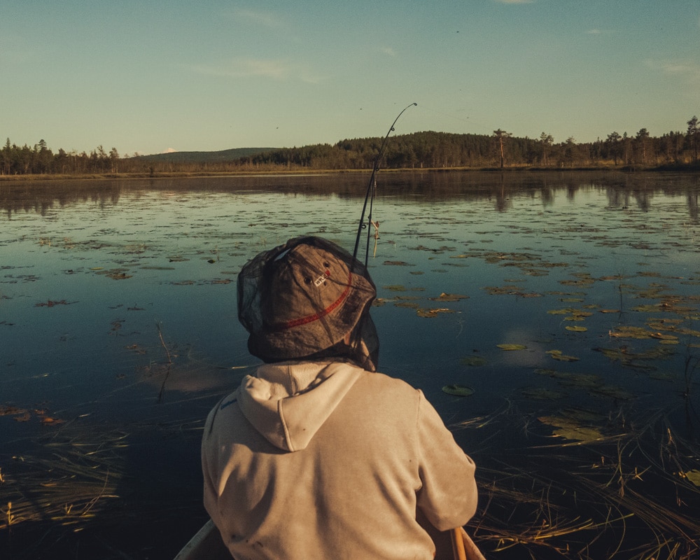 7.8.2020 Man fishing from canoe in Finnish Lapland.