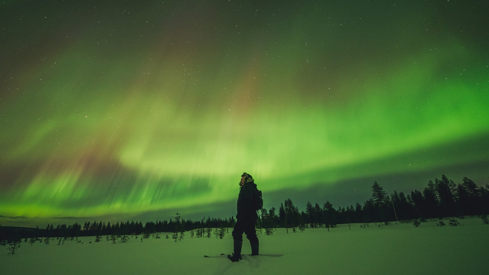 23.3.2023 Man skiing under the northern lights in Rovaniemi, Lapland.
