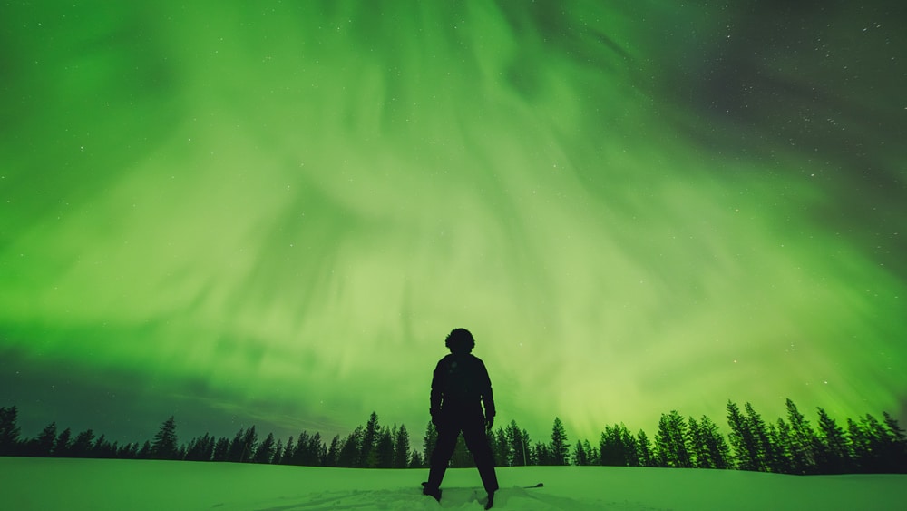 23.3.2023 Man skiing under great green northern lights in Rovaniemi, Lapland.